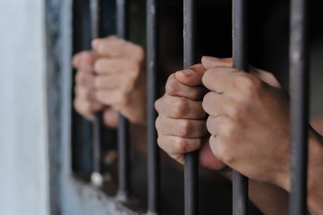 hands holding onto jail bars